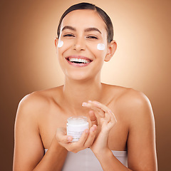 Image showing Portrait, skincare and cream with a model woman in studio on a brown background for beauty or hydration. Face, beauty and product with a happy young female holding a container to apply moisturizer