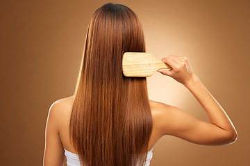 Image showing Back of hair, brush and woman in studio for beauty, wellness and keratin treatment on brown background. Hairdresser mockup, salon and girl brushing hairstyle for growth, haircare texture or cosmetics