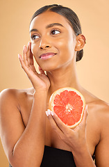 Image showing Skincare, beauty and woman with a grapefruit for a glow isolated on a studio background. Thinking, smile and an Indian model with a fruit for healthy skin, complexion and vitamin c treatment