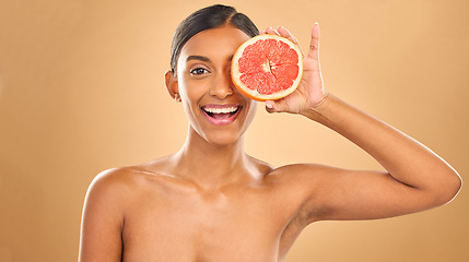 Image showing Face smile, skincare and woman with grapefruit in studio isolated on a brown background. Portrait, natural cosmetics and happy Indian female model with citrus fruit for vitamin c, nutrition or beauty