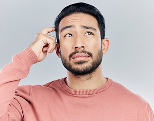 Image showing Thinking, confused and doubt with a man in studio on a gray background looking thoughtful or contemplative. Question, idea and memory with a young asian male trying to remember but feeling unsure