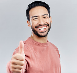 Image showing Asian man, portrait smile and thumbs up for success, good job or winning against a white studio background. Happy male face smiling and showing thumb emoji, yes sign or like for agreement or approval