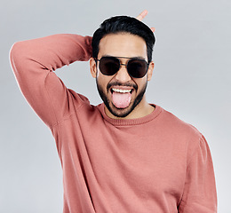 Image showing Portrait, tongue out and Asian man with sunglasses, funny and silly against a grey studio background. Face, Japanese male and guy with funky eyewear, shades and comic with humor and goofy expression