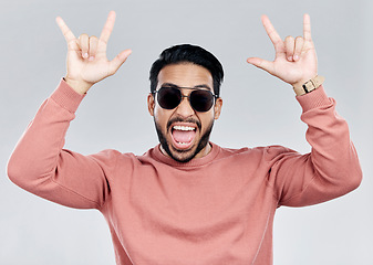 Image showing Portrait, rocker and hand gesture with a man in studio on a gray background feeling crazy or energetic. Face, rock on or hardcore and a male posing with a devil horns sign or symbol at a concert