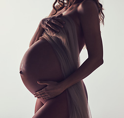 Image showing Woman, pregnant and fabric on stomach in studio with hands, touch and art by white background. Pregnancy model, shadow and mom wellness with cloth for body, belly and silhouette with dark aesthetic