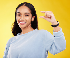 Image showing Showing, small and portrait of a woman with hands isolated on a yellow background in a studio. Happy, measurement and a girl with a review, gesturing size and opinion with fingers on a backdrop