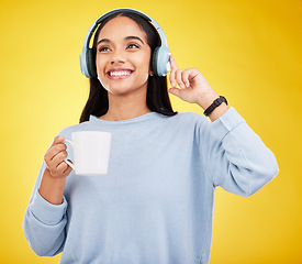 Image showing Coffee, music and headphones with woman in studio for streaming, online radio and relax. Smile, media and podcast with female isolated on yellow background for technology, listening and connection