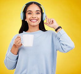 Image showing Coffee, music and headphones with portrait of woman in studio for streaming, online radio and relax. Smile, media and podcast with female on yellow background for technology, listening and connection