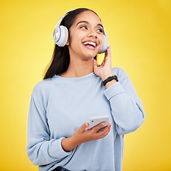 Image showing Happy, music and phone with woman in studio for streaming, online radio and audio. Smile, media and podcast with female and headphones on yellow background for technology, listening and connection