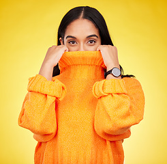 Image showing Cold, cover and portrait of a woman with a jersey isolated on a yellow background in a studio. Hiding, winter and a girl holding a jumper up for covering, warmth and bad weather on a backdrop