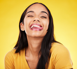 Image showing Woman, portrait smile and tongue out with silly facial expression against a yellow studio background. Happy, fun and goofy carefree female model smiling with teeth and funny face in joyful happiness