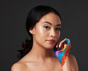 Image showing Woman, portrait and beauty with rainbow paint hand and skincare for serious face in studio. Creative skin and makeup on female aesthetic model on gray background for lgbtq color inspiration on hands