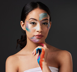Image showing Beauty, portrait and woman with paint art on hand and face in studio. Creative skin and rainbow makeup on serious female aesthetic model on gray background for lgbtq color inspiration on hands