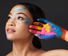 Image showing Woman, hand and beauty with rainbow paint art and face thinking in studio. Creative skin and makeup on female aesthetic model on gray background for lgbtq color inspiration and hope or peace on hands