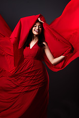 Image showing Woman, beauty and fashion, red art on dark background with energy and aesthetic movement. Flowing silk motion, fantasy and artistic model with smile in creative fabric designer dress in studio