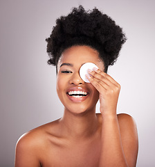 Image showing Black woman, skincare and cotton on eye in studio with cleaning, makeup removal or laugh by background. Young model, wipe and clean skin for natural glow, comic smile or cosmetic health for self care