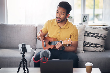 Image showing Podcast, guitar and phone with a man online to talk and coach during live streaming lesson. Asian male person talking on home sofa with a ukulele as content creator teaching music on education blog