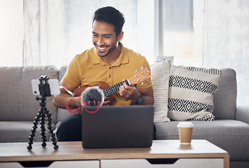 Image showing Guitar, streaming and phone with a man talking online to coach during live lesson. Asian male influencer happy on home sofa with a ukulele as content creator teaching music on education podcast blog