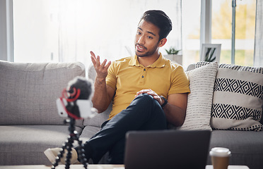 Image showing Content creator, laptop and phone, Indian man on sofa recording webinar, broadcast and live streaming in home. Internet, webcam and online influencer talking with equipment for social media channel.
