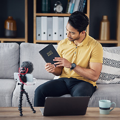 Image showing Christian man, bible and study with phone and microphone online while live streaming. Asian male on home sofa with holy book on religion as blog content creator or influencer teaching on podcast