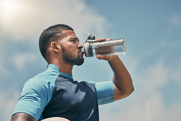 Image showing Drinking water, fitness and training with a sports man outdoor for a competitive game or event. Exercise, hydration and health with a male athlete taking a drink from a bottle during a break or rest