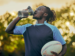 Image showing Drinking water, fitness and rugby with a sports black man outdoor for a competitive game or event. Exercise, training and health with a male athlete taking a drink from a bottle during a break