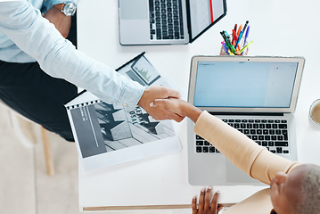 Image showing Creative business people, handshake and laptop above on mockup screen for teamwork collaboration at office. Top view of employee designers shaking hands for meeting, partnership or startup agreement