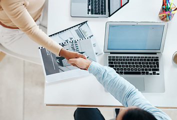 Image showing Creative business people, handshake and laptop above on mockup screen for teamwork collaboration at office. Top view of employee designers shaking hands for meeting, partnership or startup agreement
