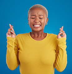 Image showing Nervous, fear and fingers crossed by desperate black woman isolated against a studio blue background. Hope, luck and wishing young female doing wish hand gesture worried, miracle and worried