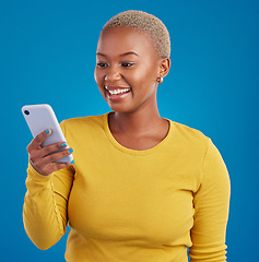 Image showing Phone, happy and black woman typing in studio for social media, text message and browse website. Communication mockup, technology and girl on internet, networking and chat online on blue background