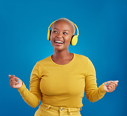 Image showing Black woman with headphones, dancing and listen to music, rhythm and fun with freedom on blue background. Happy female with yellow aesthetic, streaming radio with dance and carefree in studio