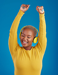 Image showing Black woman with headphones, dance and listening to music with rhythm and fun with freedom on blue background. Happy female with arms raised, streaming radio with dancing and carefree in studio