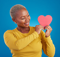 Image showing Paper, heart and happy with black woman in studio for love, date and kindness. Invitation, romance and feelings with female and shape isolated on blue background for emotion, support and affectionate