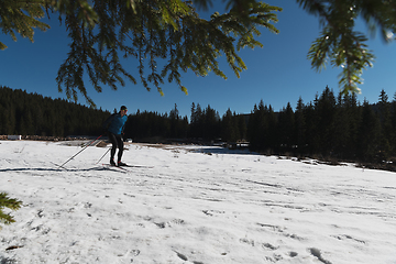 Image showing Nordic skiing or Cross-country skiing classic technique practiced by man in a beautiful panoramic trail at morning.