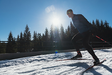 Image showing Nordic skiing or Cross-country skiing classic technique practiced by man in a beautiful panoramic trail at morning.