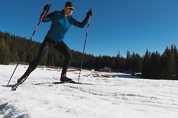 Image showing Nordic skiing or Cross-country skiing classic technique practiced by man in a beautiful panoramic trail at morning.