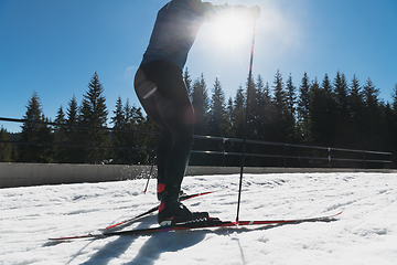 Image showing Nordic skiing or Cross-country skiing classic technique practiced by man in a beautiful panoramic trail at morning.