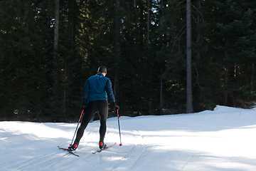 Image showing Nordic skiing or Cross-country skiing classic technique practiced by man in a beautiful panoramic trail at morning.