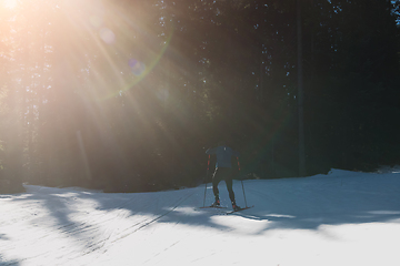 Image showing Nordic skiing or Cross-country skiing classic technique practiced by man in a beautiful panoramic trail at morning.