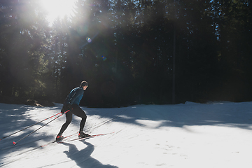 Image showing Nordic skiing or Cross-country skiing classic technique practiced by man in a beautiful panoramic trail at morning.