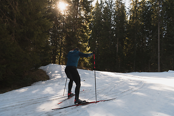 Image showing Nordic skiing or Cross-country skiing classic technique practiced by man in a beautiful panoramic trail at morning.