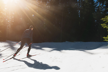 Image showing Nordic skiing or Cross-country skiing classic technique practiced by man in a beautiful panoramic trail at morning.