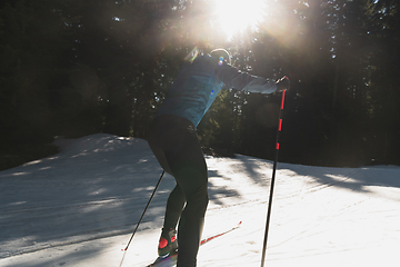 Image showing Nordic skiing or Cross-country skiing classic technique practiced by man in a beautiful panoramic trail at morning.