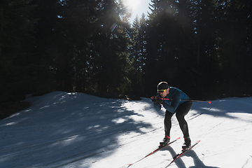 Image showing Nordic skiing or Cross-country skiing classic technique practiced by man in a beautiful panoramic trail at morning.