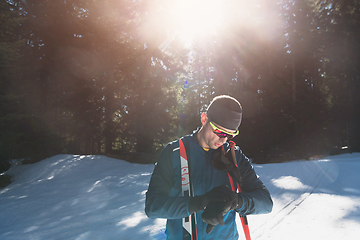 Image showing Portrait handsome male athlete with cross country skis in hands and goggles, training in snowy forest. Healthy winter lifestyle concept.