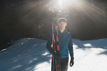 Image showing Portrait handsome male athlete with cross country skis in hands and goggles, training in snowy forest. Healthy winter lifestyle concept.