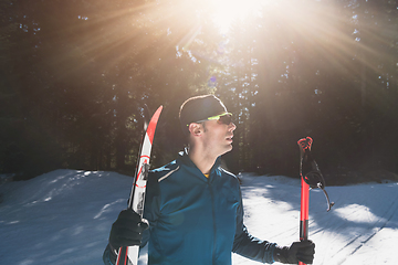 Image showing Portrait handsome male athlete with cross country skis in hands and goggles, training in snowy forest. Healthy winter lifestyle concept.