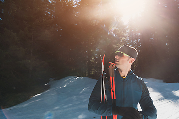 Image showing Portrait handsome male athlete with cross country skis in hands and goggles, training in snowy forest. Healthy winter lifestyle concept.