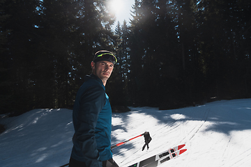 Image showing Portrait handsome male athlete with cross country skis in hands and goggles, training in snowy forest. Healthy winter lifestyle concept.