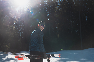 Image showing Portrait handsome male athlete with cross country skis in hands and goggles, training in snowy forest. Healthy winter lifestyle concept.